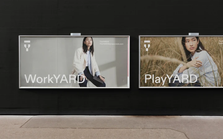 Two billboard displays mounted on a dark exterior wall, featuring WorkYARD and PlayYARD advertisements with models.