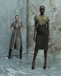 Two female models posing in a grand stone-clad architectural interior for the Cue SS24 collection campaign.