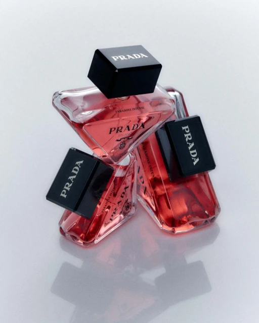 Three Prada Paradoxe Intense perfume bottles are stacked against a light background, showcasing the fragrance and its geometric bottle design.