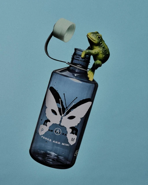 Blue water bottle with a white cap and a green toy frog clinging to the neck, set against a solid light blue background.