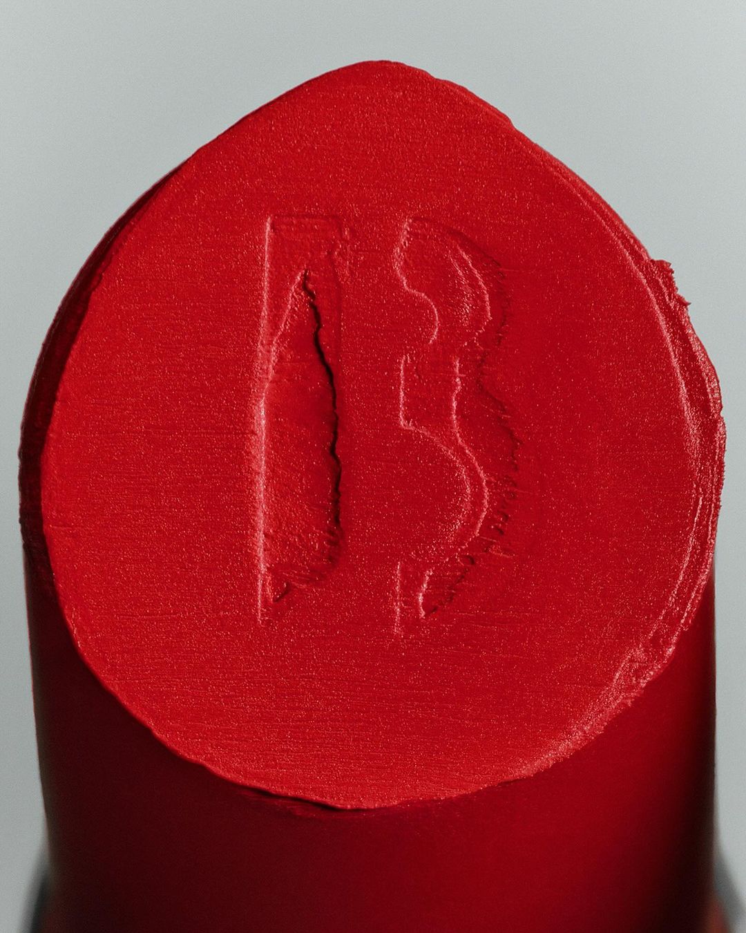 Macro photograph of red lipstick with an embossed logo, showcasing beauty and cosmetics in a studio setting.