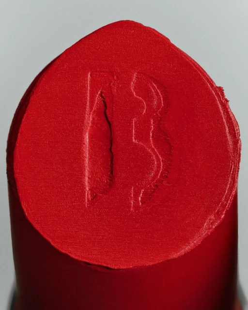 Macro photograph of red lipstick with an embossed logo, showcasing beauty and cosmetics in a studio setting.