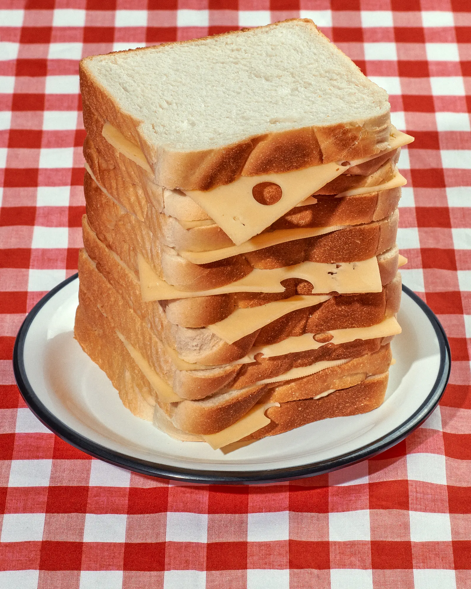 Tower of toast and cheese on a plate, set against a red-and-white checkered background for a food or snack concept.