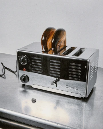 Toaster with two slices of toast on a metallic surface, shot in a photo studio with soft lighting. Rowlett brand.