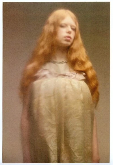 Portrait of a redhead woman with pale skin in a vintage dress with ruffles. The photo has an intentional soft focus look.