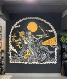 Mural illustration by Kentaro Yoshida of a skeleton riding a motorcycle with a tiger passenger, holding drinks under a yellow moon.