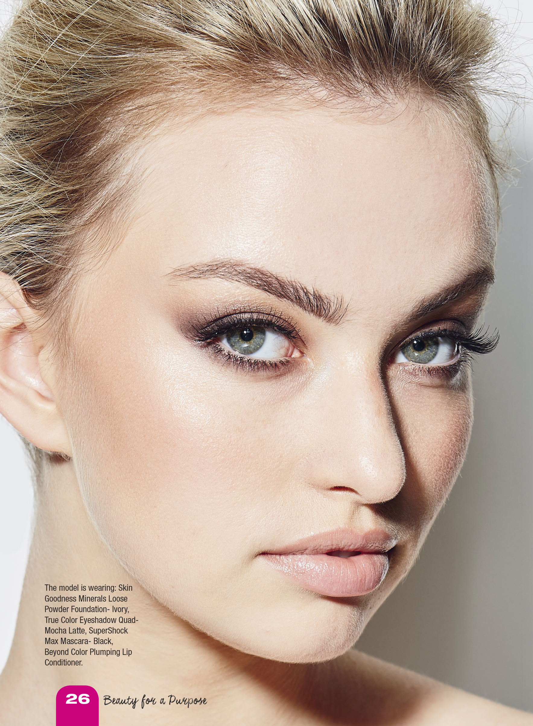 Close-up portrait of a young adult woman with light skin and blonde hair, wearing eye makeup and light pink lipstick in a beauty shot.