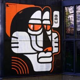 Large-scale mural illustration of a stylized character profile in orange, black, and white by ETTOJA.
