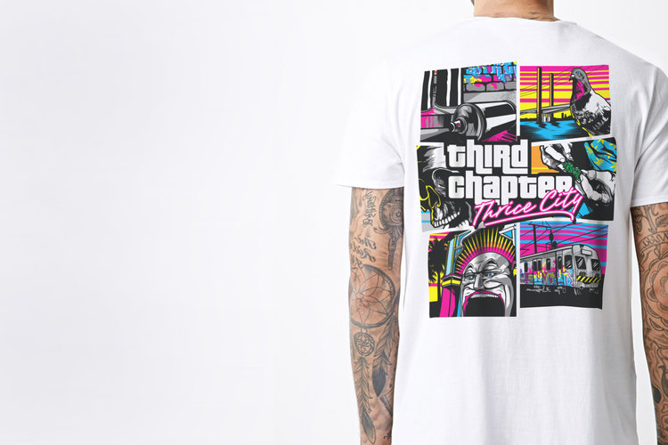 Person wears a white t-shirt with colorful graphic art of comic-book-style panels printed on the back against a plain white backdrop.