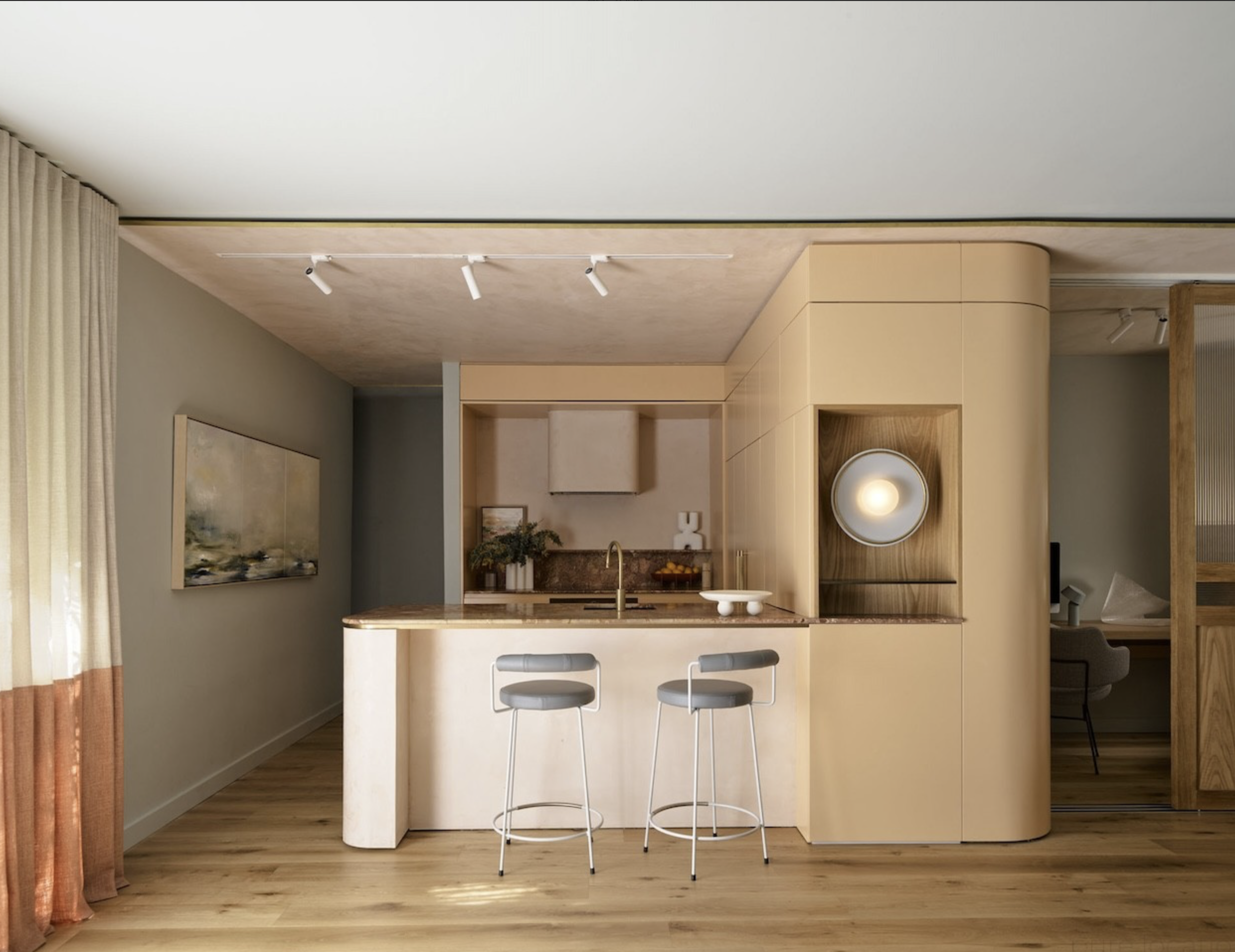 Modern kitchen interior with a marble countertop island, two gray stools, neutral cabinetry, and a minimalist aesthetic in a home setting.