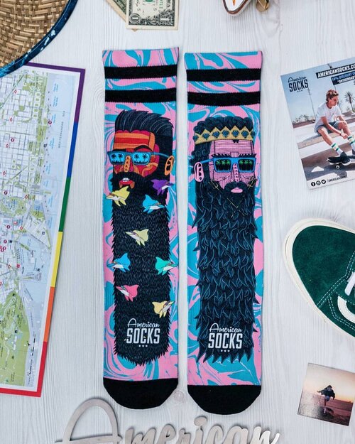 Two socks with cartoon-style designs of men wearing glasses, set against a backdrop of travel-themed items and vibrant colors.