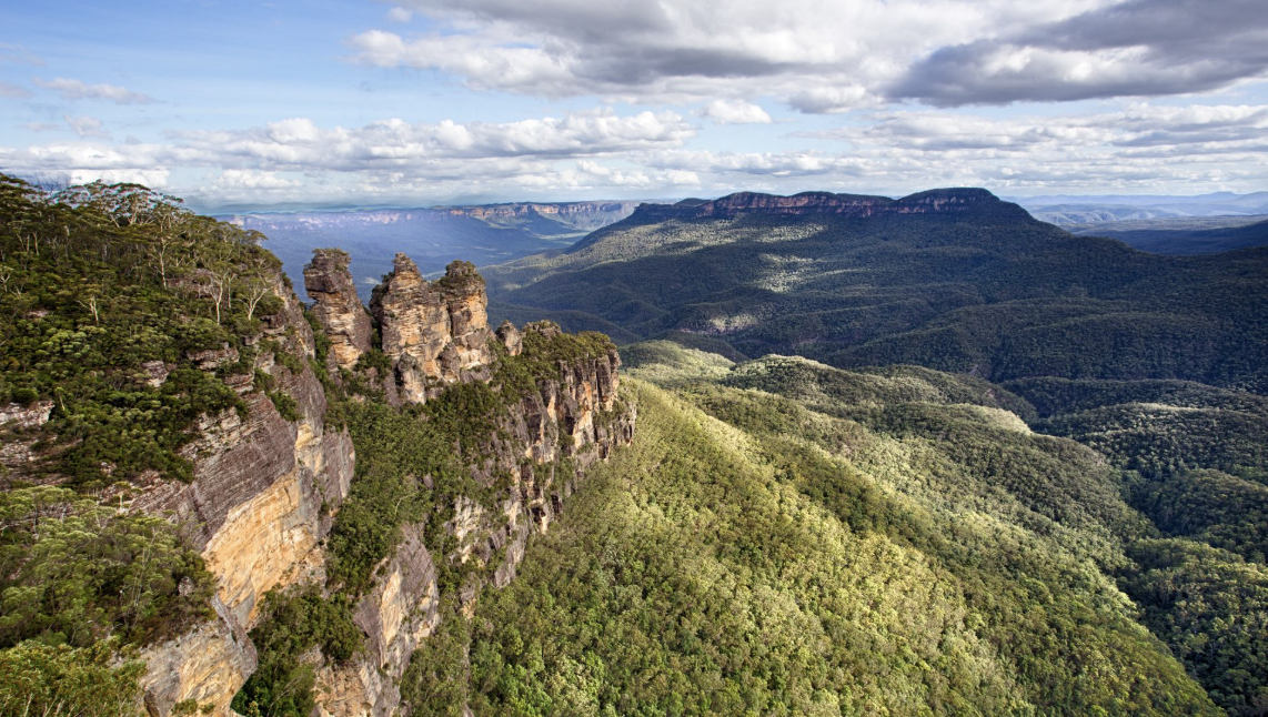 Scenic vista of the Three Sisters rock formation in Blue Mountains National Park, New South Wales, Australia; lush forest landscape.