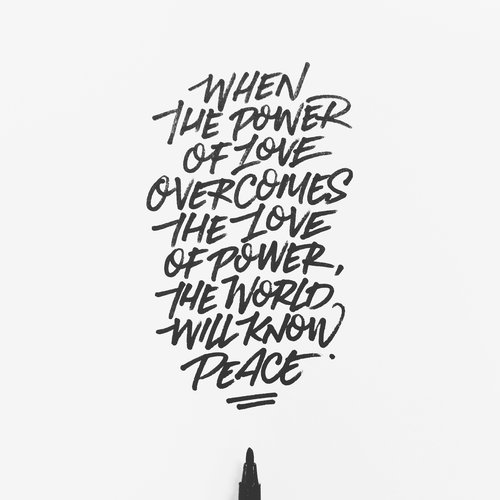 Close-up of hand-lettered quote on white paper in black ink: "When the power of love overcomes the love of power, the world will know peace."