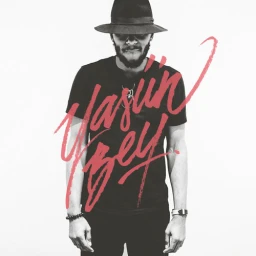 Black and white portrait of a man wearing a fedora hat and dark t-shirt with red handwritten script overlaid