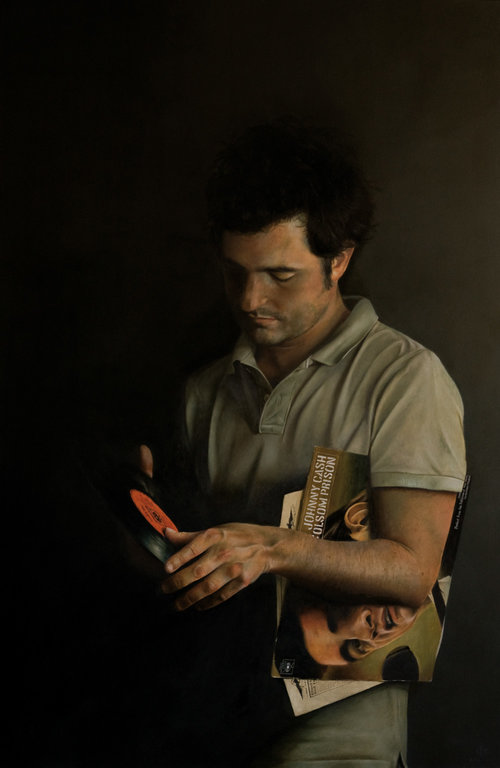 Man holding a vinyl record and a Johnny Cash album in a dimly lit setting, creating a vintage and musical atmosphere.
