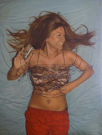 Smiling woman lying on a blue sheet, holding a cassette tape, with cassette tape strands wrapped around her body and waist.