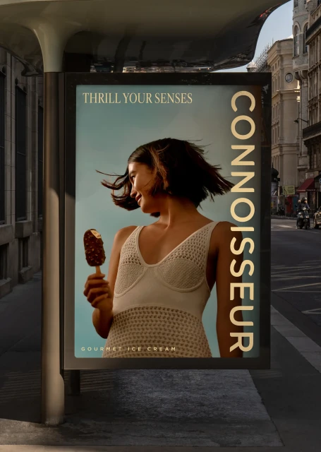 Outdoor ad for Connoisseur gourmet ice cream shows a woman in a knitted dress holding an ice cream bar on a city street.