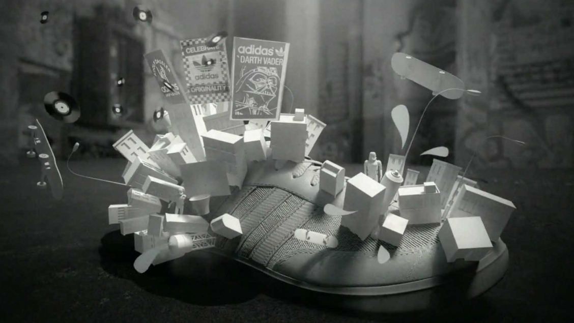 Conceptual monochrome image featuring an Adidas shoe surrounded by floating skateboards, records, and miniaturized cityscapes and posters.