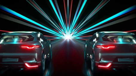 Two cars speeding down a highway with a futuristic cyan and red light tunnel backdrop, directed by Anders Schroder.
