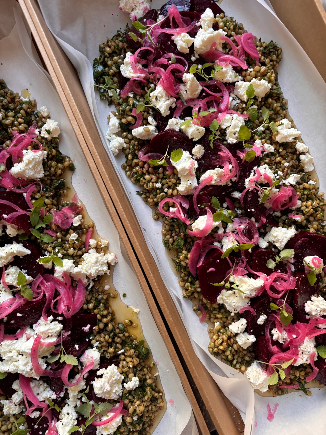 Overhead food photography of gourmet grain salad topped with red beets, pickled red onion, and crumbled white goat cheese.