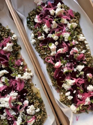 Overhead food photography of gourmet grain salad topped with red beets, pickled red onion, and crumbled white goat cheese.