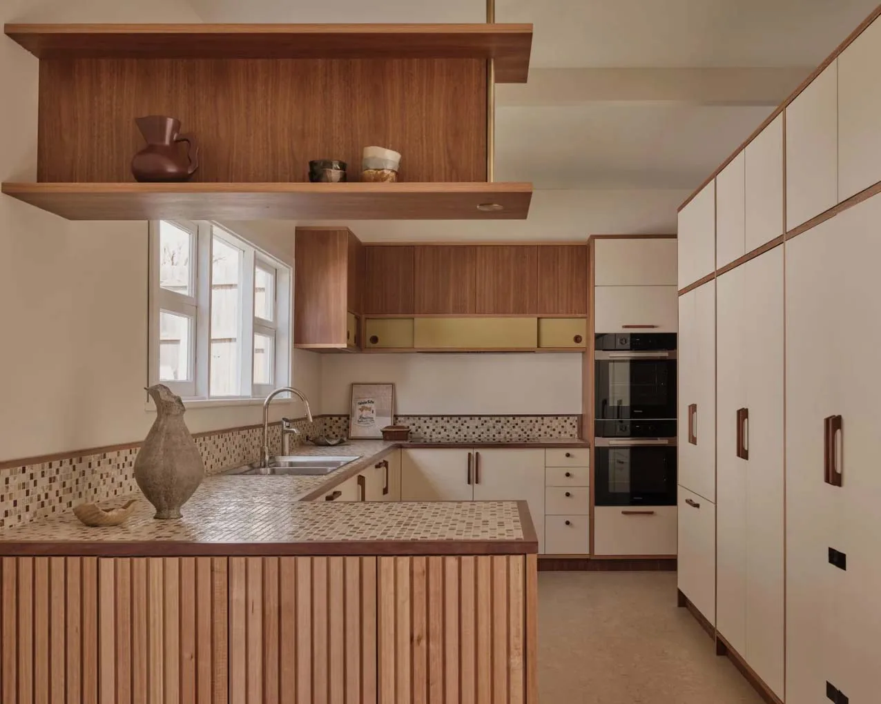 Modern kitchen interior featuring wood cabinetry, tiled countertops, and a variety of dishes and kitchenware displayed.