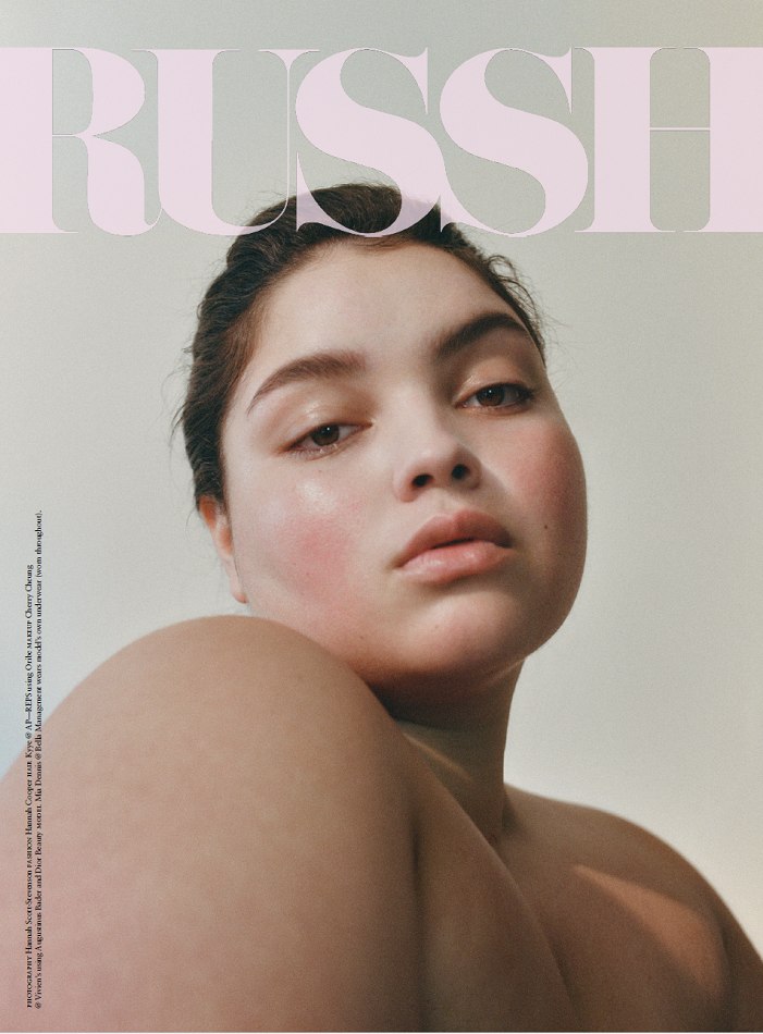 Close-up portrait of a young woman with dark hair and fair skin, posing for a magazine cover with a soft, diffused lighting.