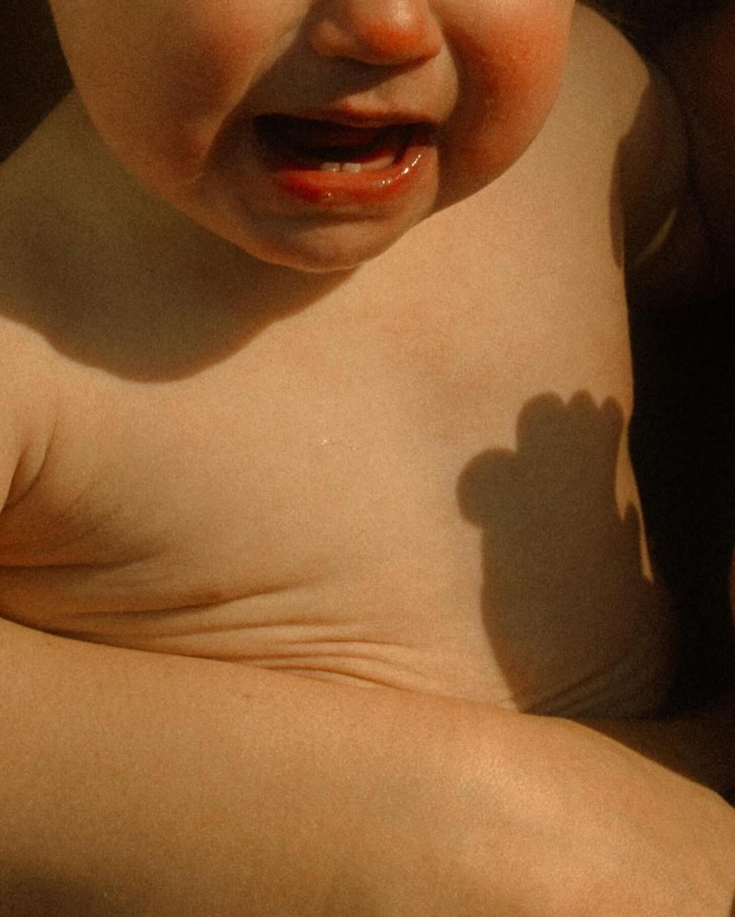 Close-up of a young child's face with an open mouth, appearing to be crying, capturing the raw emotion and vulnerability of infancy.
