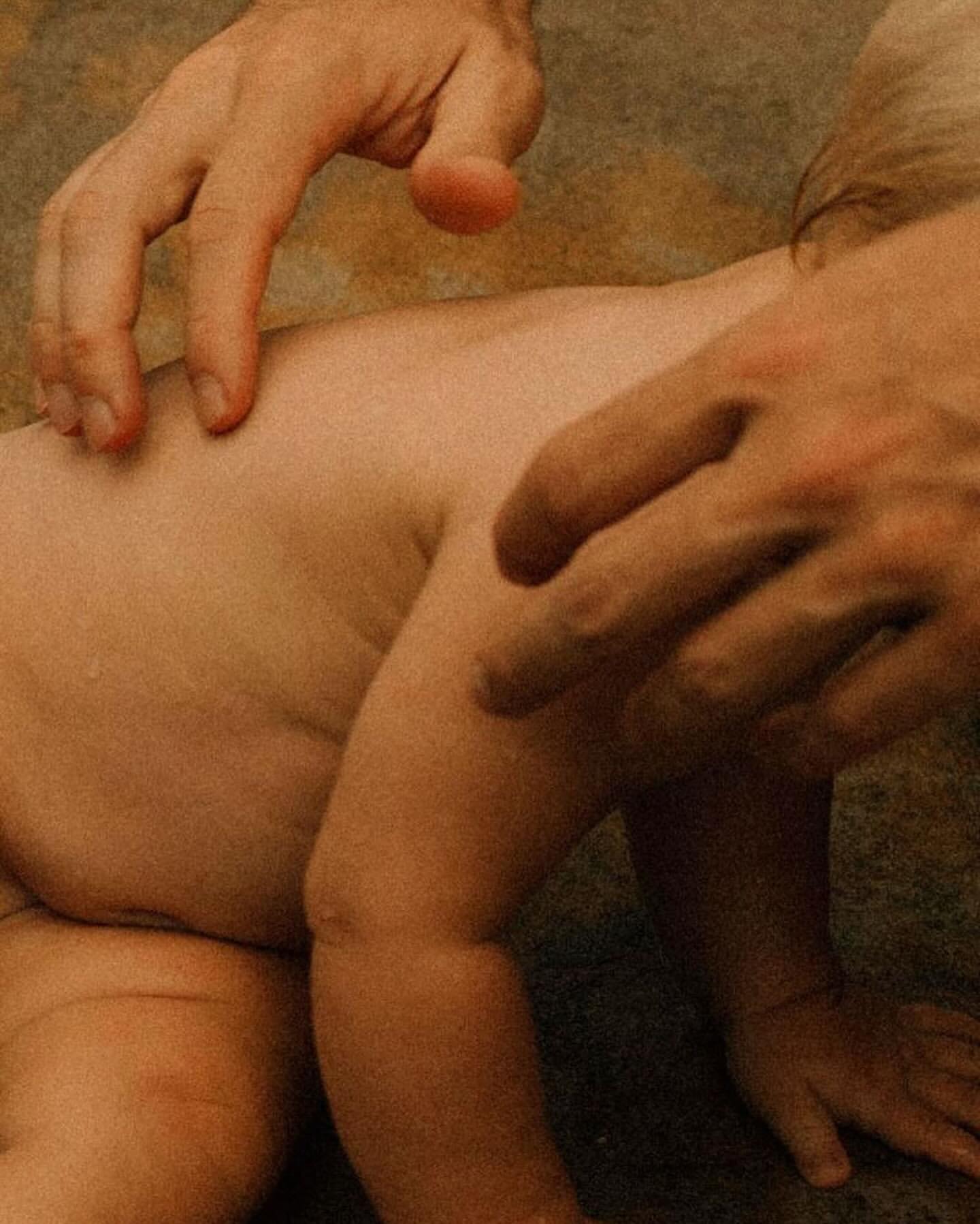 Close-up of a baby's back and buttocks being touched and examined by the hands of an adult with a warm, neutral-toned background.