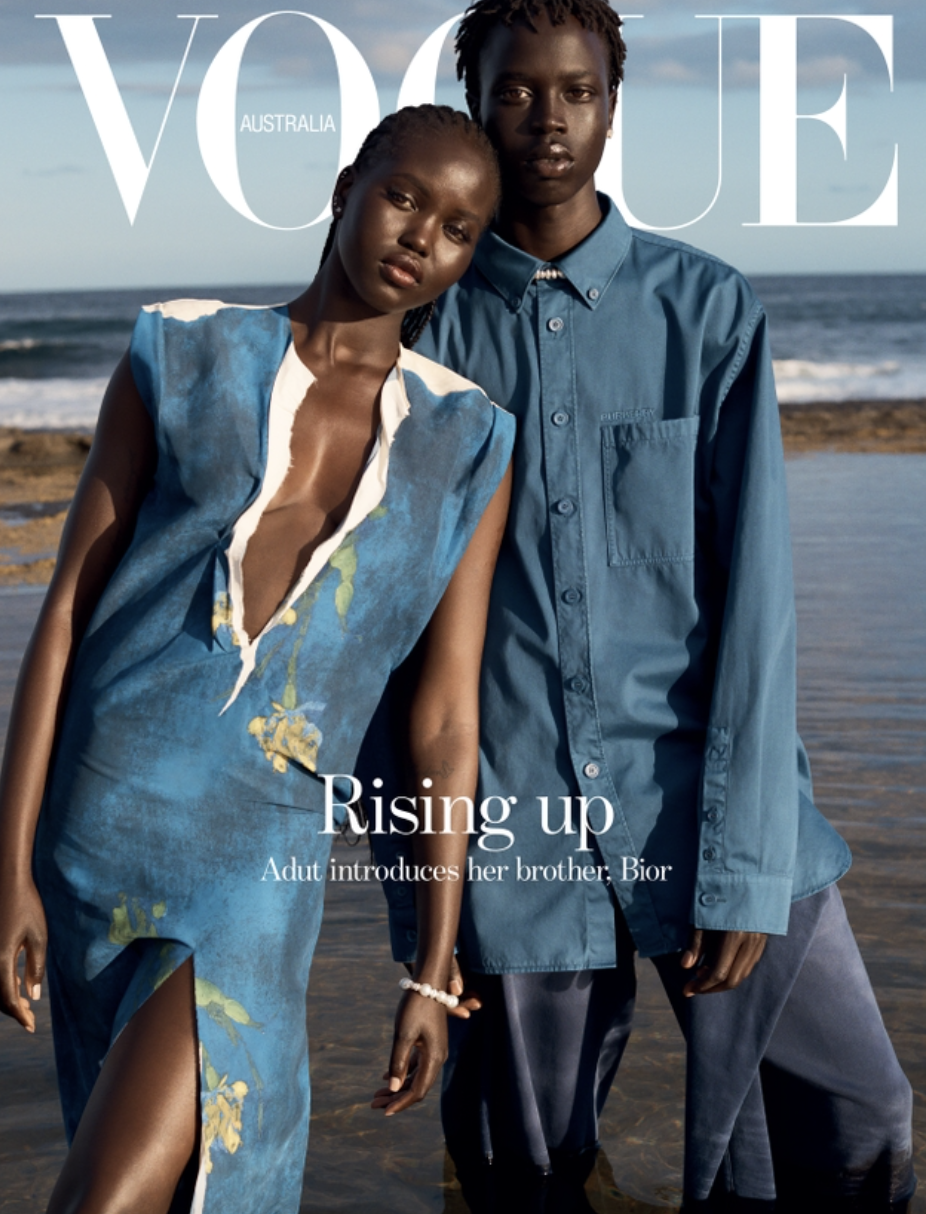 Vogue Australia cover featuring a dark-skinned woman in a blue dress next to a dark-skinned man in a blue shirt, posing on a beach.