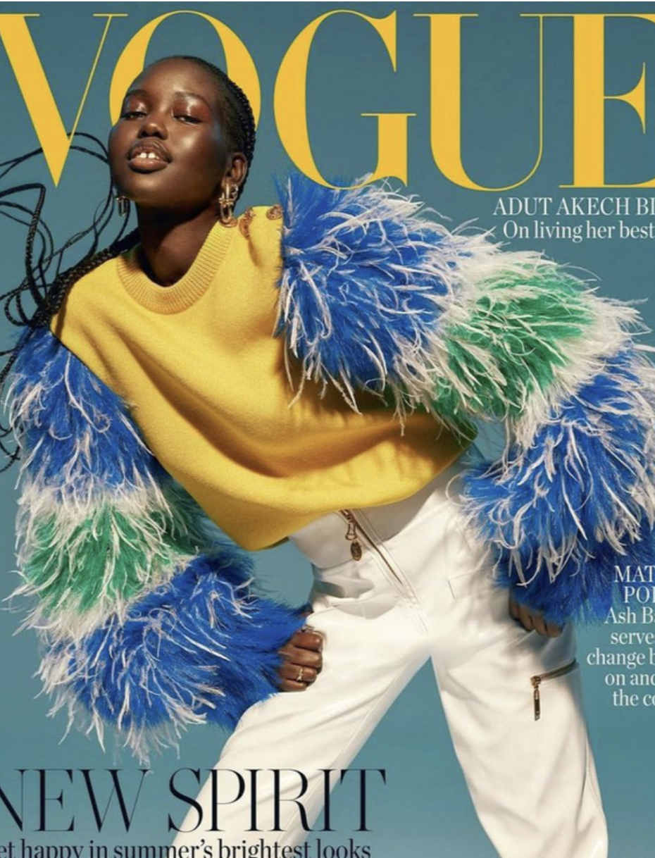 Vogue cover featuring a black female model with braided hair, wearing a yellow sweater with feathered sleeves and white pants.