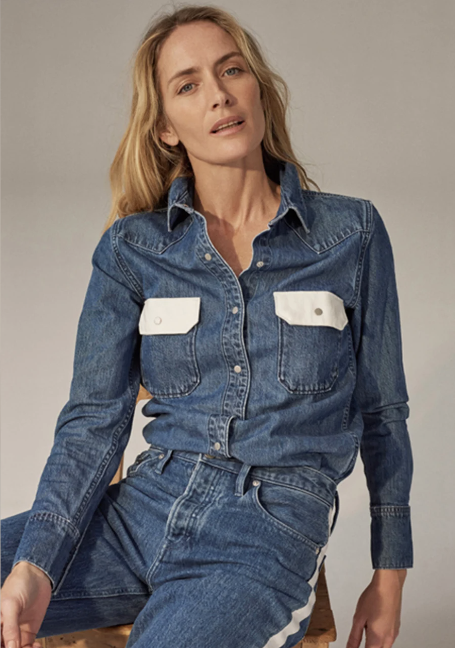 Blonde woman wearing a denim shirt and jeans in a studio setting, medium shot, fashion photography.