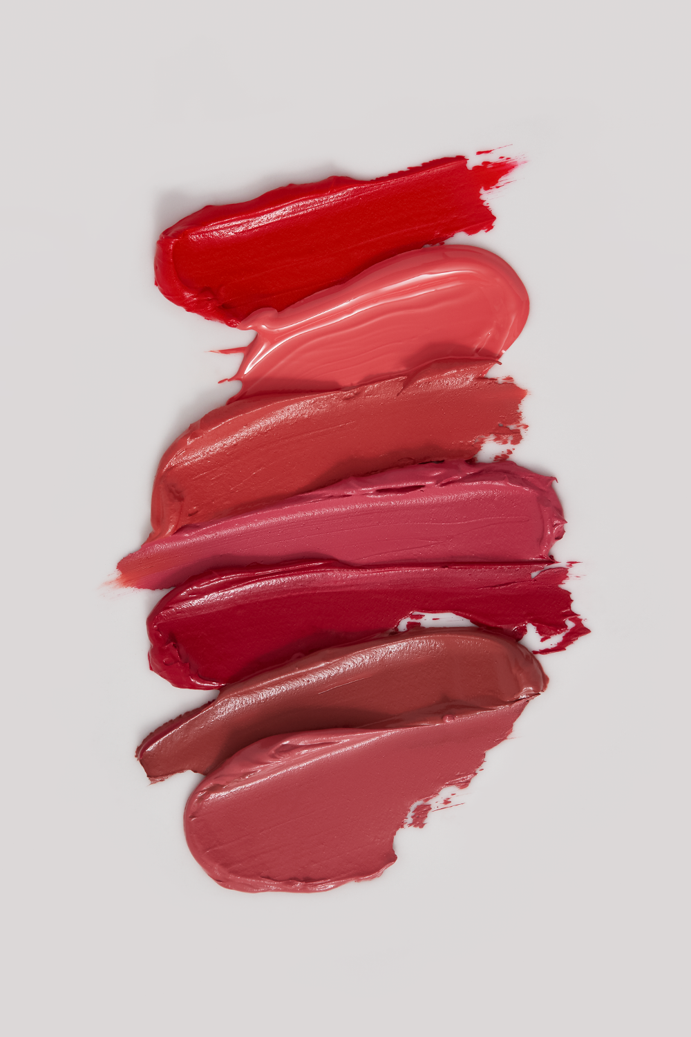 Close-up of lipstick swatches in shades of red, pink, and brown on a white background, beauty and cosmetics product photography.
