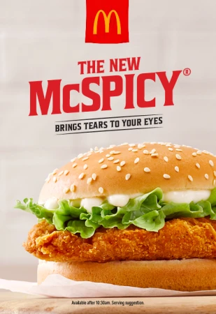 Close-up of a McSpicy burger with lettuce and mayonnaise. The McSpicy logo is visible above the burger on a light background.