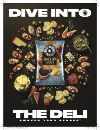 Flat lay of potato chip bag surrounded by gourmet food items like cheese, crackers, and figs on dark background.