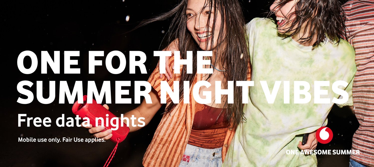 Two women smile with wet hair and casual outfits in a dark outdoor setting, holding a red speaker with promotional text overlaid.