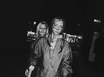 Monochrome fashion photography of two women walking outdoors at night with dark apparel and dramatic eye makeup captured by Lester Jones.