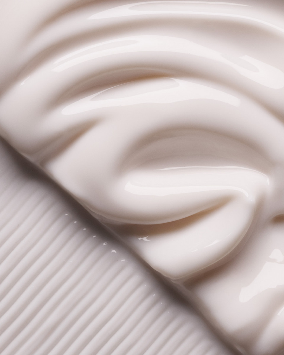 Close-up of a smooth, light beige cream with a rippled pattern covering the upper portion and grooved texture in the lower left.