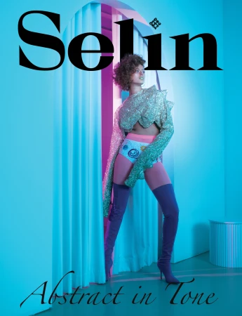 A young woman poses in a sparkling shirt and thigh-high boots against a blue backdrop with fashion magazine typography and structural shapes.