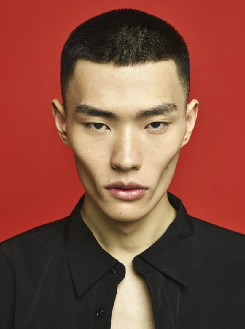 Portrait of a man with short dark hair wearing a black shirt against a red background