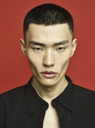 Portrait of a man with short dark hair wearing a black shirt against a red background