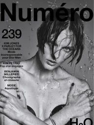 Model with wet hair and splashing water droplets on face against a grey background for Numero magazine