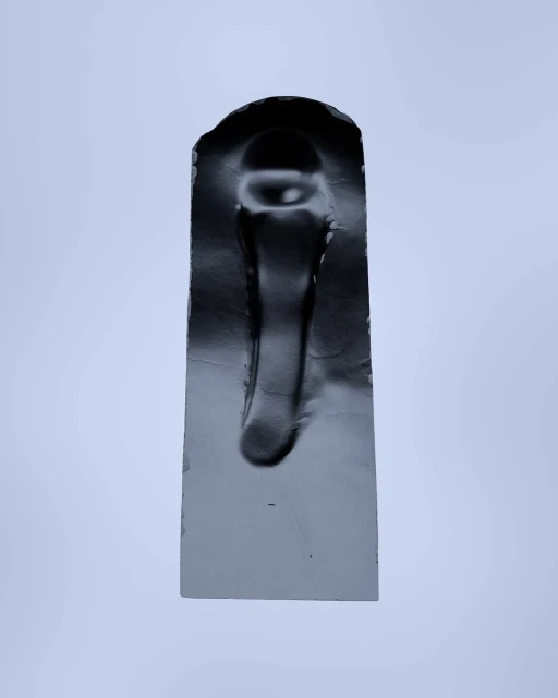 Abstract photograph of a solid, black, rectangular sculpture with an arched top against a plain, light grey background.