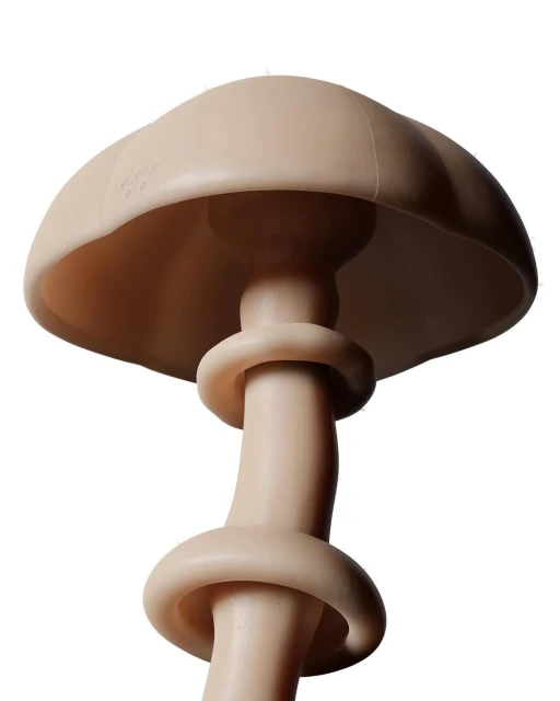 Low-angle, close-up studio shot of a mushroom-shaped sculpture in a light tan color. The piece features rounded forms and smooth texture.