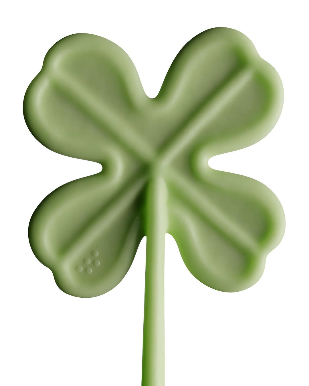 Close-up of a green four-leaf clover lollipop on a white background, symbolizing luck and St. Patrick's Day.