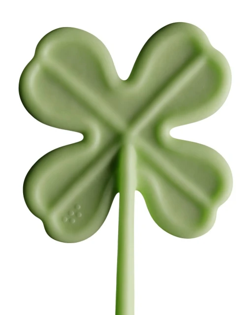 Close-up of a green four-leaf clover lollipop on a white background, symbolizing luck and St. Patrick's Day.