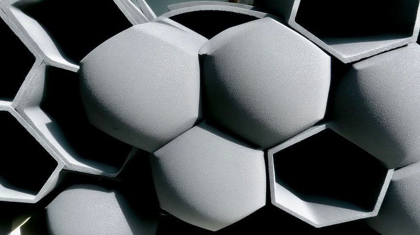 Close-up photo of gray, geometric, and textured surface formed by repeating hexagonal shapes, creating a modern architectural background.