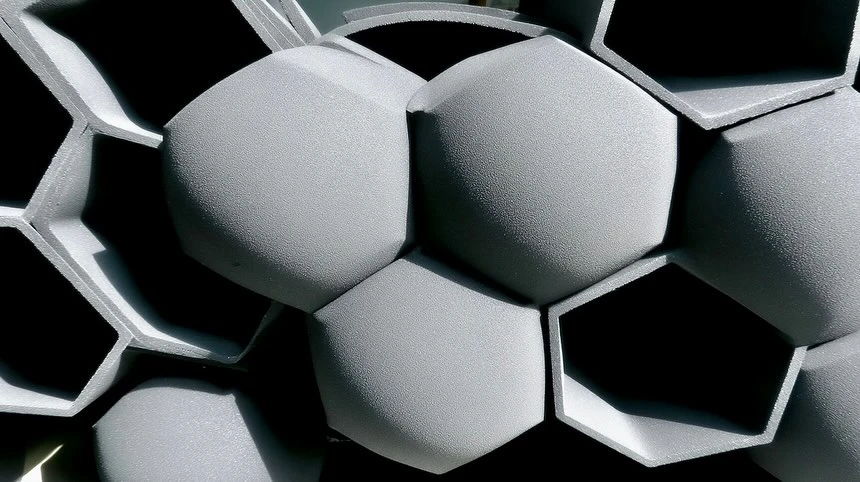 Close-up photo of gray, geometric, and textured surface formed by repeating hexagonal shapes, creating a modern architectural background.