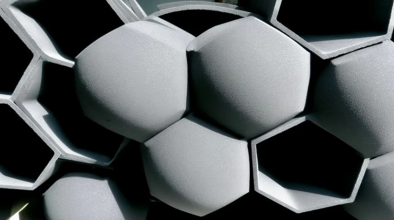 Close-up photo of gray, geometric, and textured surface formed by repeating hexagonal shapes, creating a modern architectural background.