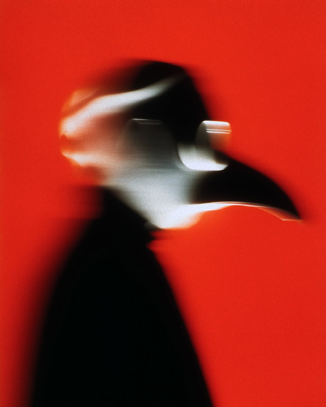 Abstract blurred photo of a person in a black plague doctor mask against a vibrant red backdrop, creating a mysterious and eerie atmosphere.